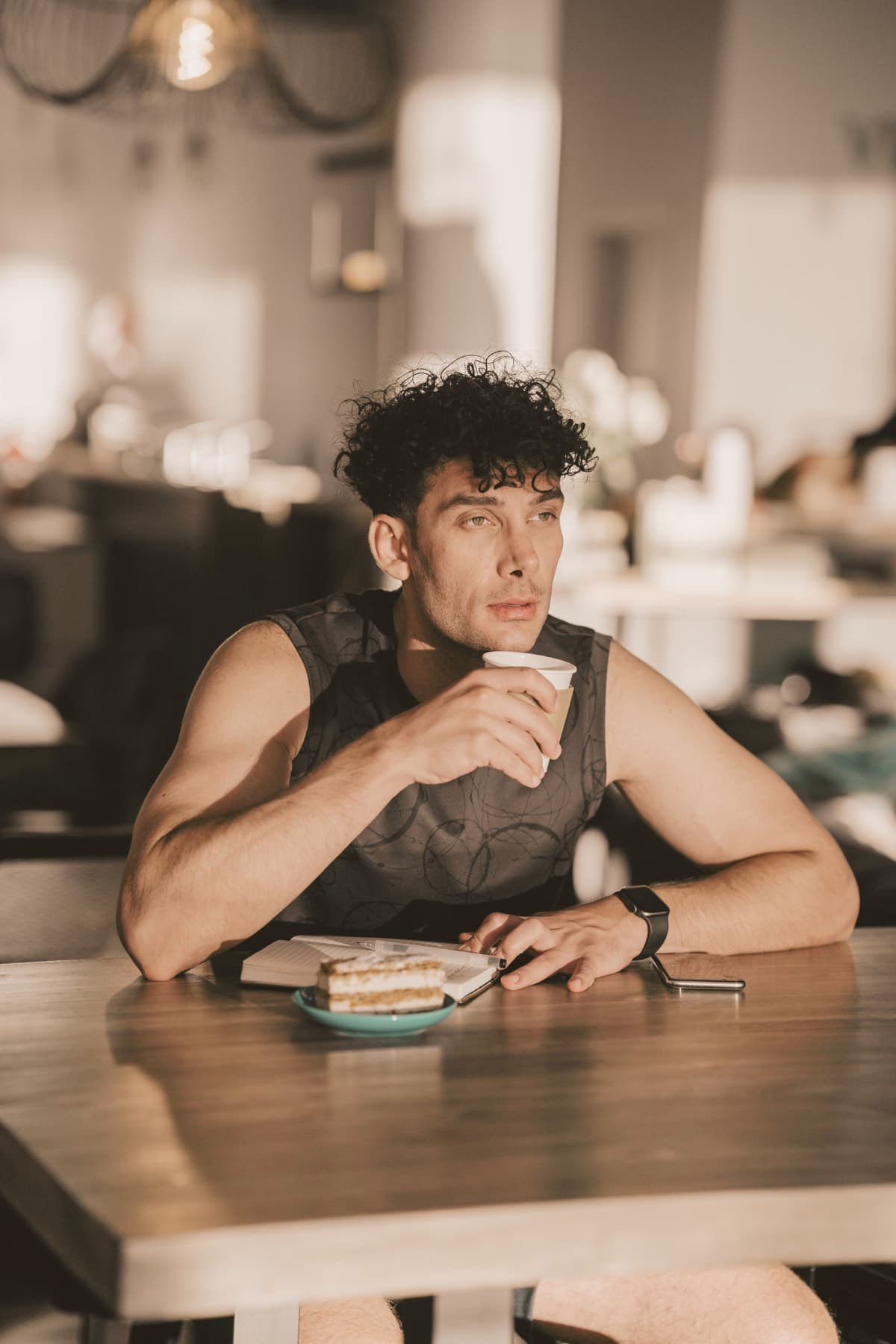 Homme attablé devant un café et une petite part de gâteau